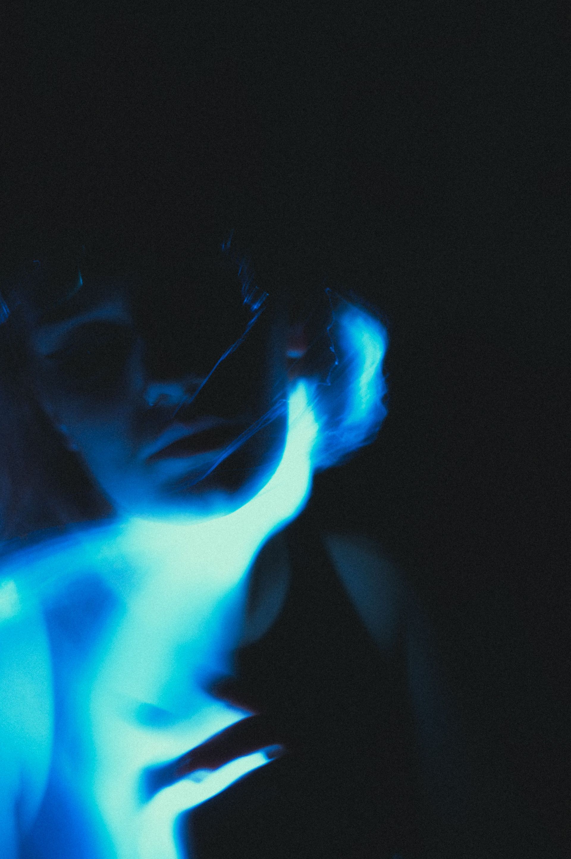 Mysterious silhouette portrait illuminated by vibrant blue light aura.